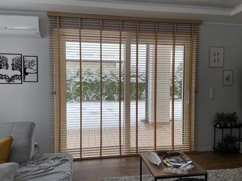 Żaluzje drewniane 50 mm w salonie z dużym oknem, realizacja Modern Line