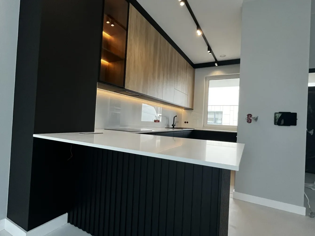 Kuchnia z ciemną wyspą ryflowaną i frontami w dekorze dębu, realizacja Modern Line